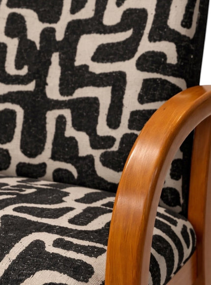 Close-up of the Vaya Home Contour accent chair showing the curved wood armrest and black-and-cream abstract patterned upholstery.