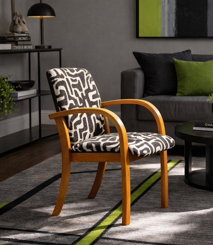 Vaya Home Contour accent chair with curved wood arms and black-and-cream abstract patterned upholstery, styled in a modern living room.