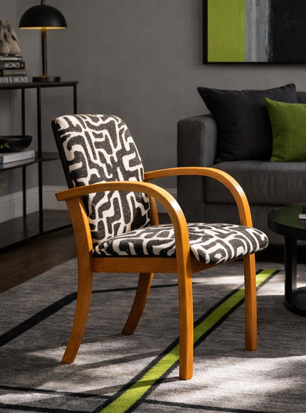 Vaya Home Contour accent chair with curved wood arms and black-and-cream abstract patterned upholstery, styled in a modern living room.