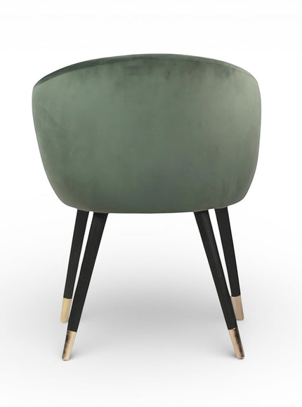Back view of the Vaya Home Cushion accent chair featuring a rounded backrest, green velvet upholstery, and black legs with gold caps.