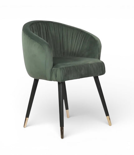 Front angled view of the Vaya Home Cushion accent chair with green velvet upholstery, channel-tufted inner back, and black legs with gold caps.
