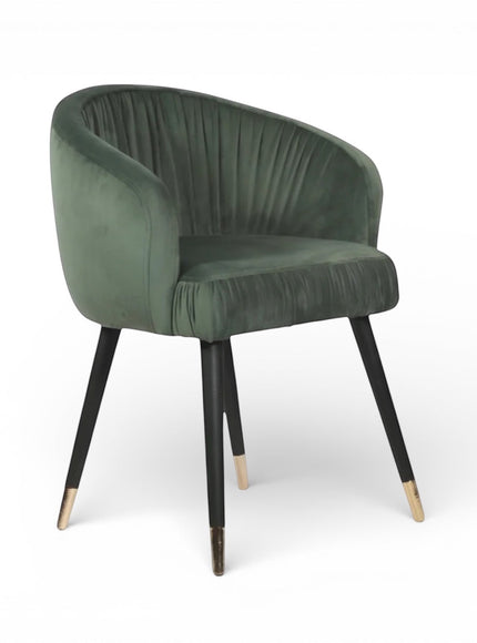 Front angled view of the Vaya Home Cushion accent chair with green velvet upholstery, channel-tufted inner back, and black legs with gold caps.