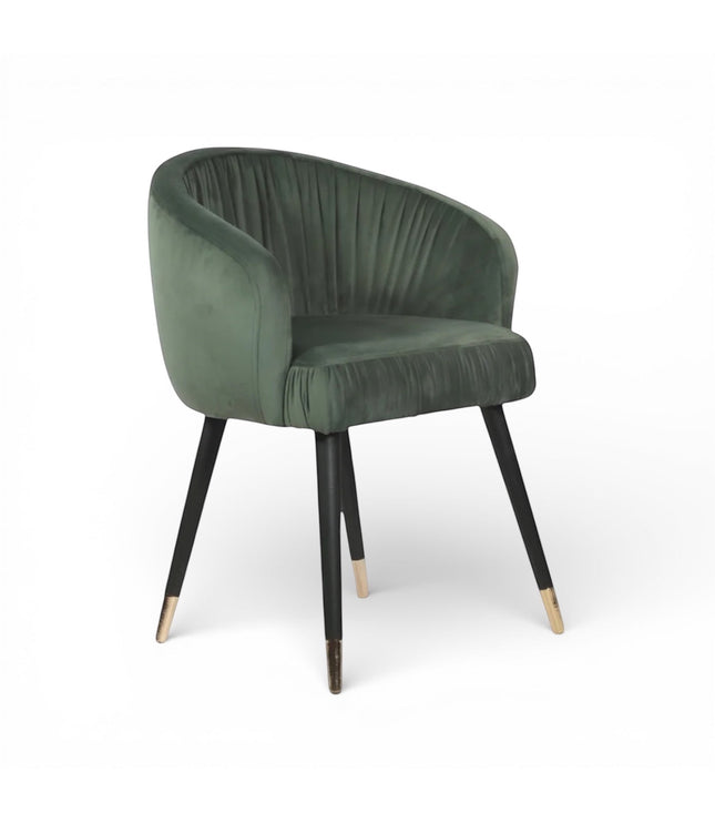 Front angled view of the Vaya Home Cushion accent chair with green velvet upholstery, channel-tufted inner back, and black legs with gold caps.