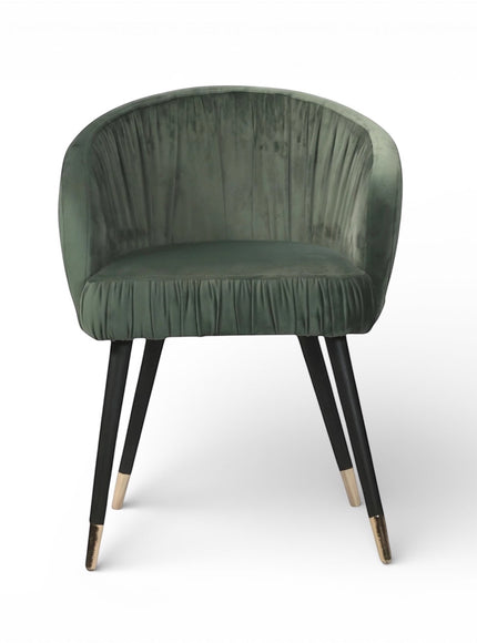 Front view of the Vaya Home Cushion accent chair featuring green velvet upholstery, a channel-tufted inner back, and black legs with gold caps.