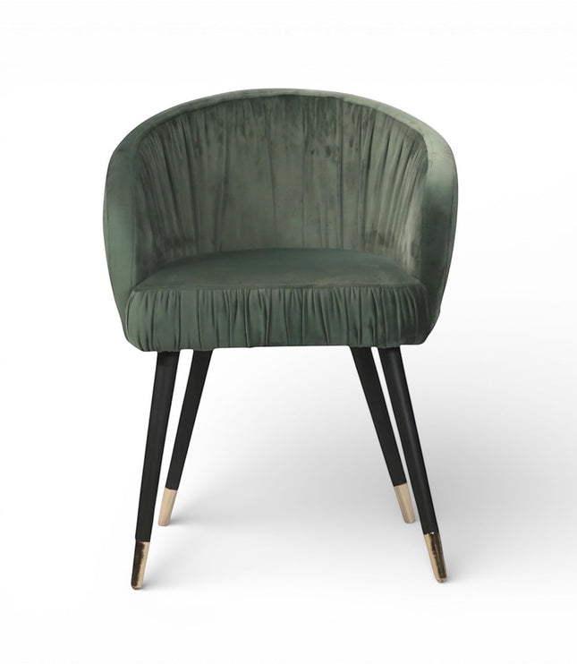 Front view of the Vaya Home Cushion accent chair featuring green velvet upholstery, a channel-tufted inner back, and black legs with gold caps.