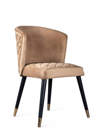 Front angled view of the Vaya Home Diamante dining chair with beige upholstery, cushioned seat, and black tapered legs with gold caps.
