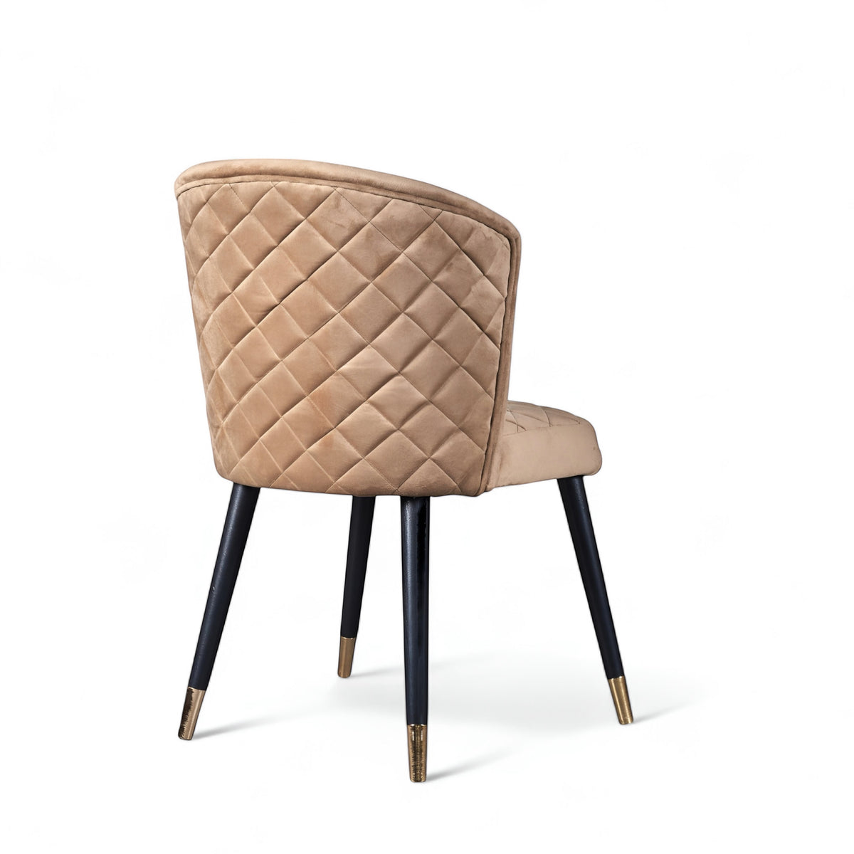 Rear angled view of the Vaya Home Diamante dining chair featuring beige upholstery, diamond-quilted back detail, and black tapered legs with gold caps.