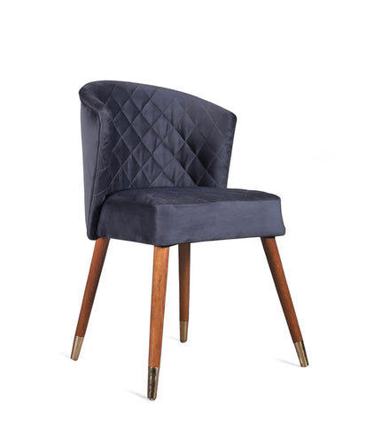 Front angled view of the Vaya Home Diamante dining chair with dark blue upholstery, diamond-quilted back detail, and tapered wood legs.