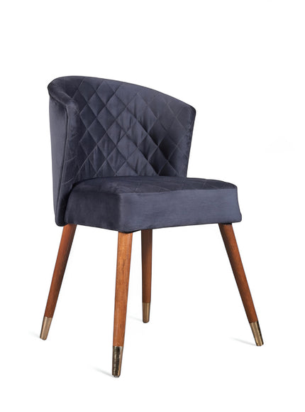Front angled view of the Vaya Home Diamante dining chair with dark blue upholstery, diamond-quilted back detail, and tapered wood legs.