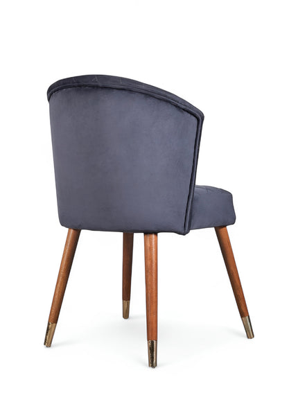 Rear angled view of the Vaya Home Diamante dining chair featuring dark blue upholstery and tapered wood legs.