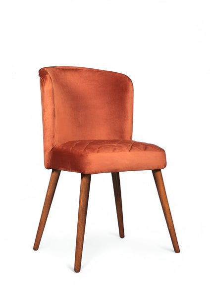 Front angled view of the Vaya Home Inverto dining chair with orange upholstery, curved backrest, and tapered wood legs with gold caps.