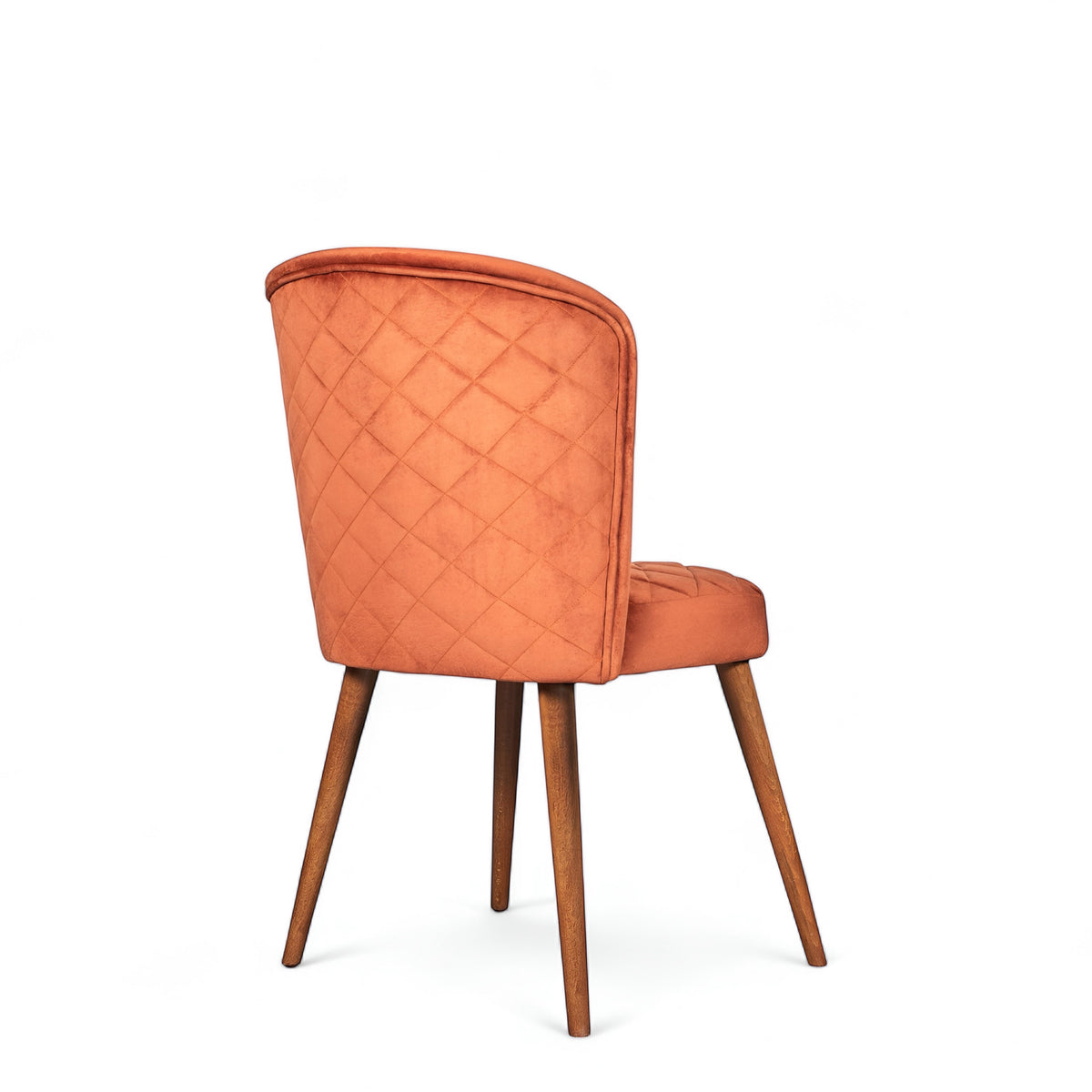 Rear angled view of the Vaya Home Inverto dining chair showing orange upholstery, quilted backrest detail, and wood legs with gold caps.