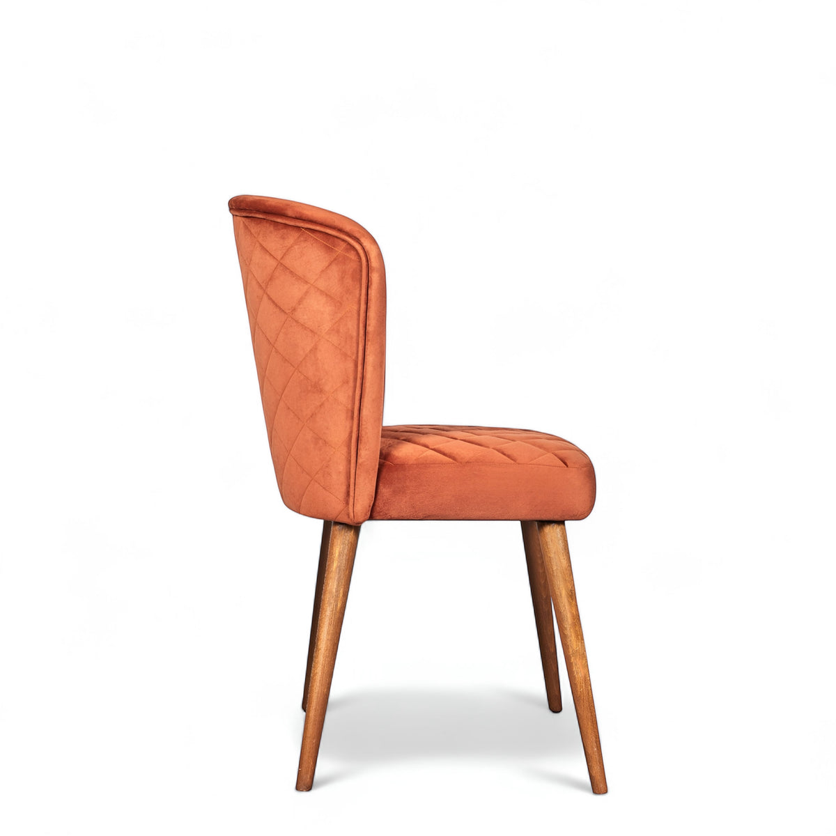 Side view of the Vaya Home Inverto dining chair with orange upholstery, quilted back detail, and tapered wood legs with gold caps.