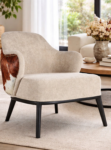 Vaya Home Kalv accent chair with beige upholstery, brown cowhide outer back, and black legs, styled in a bright modern living room.