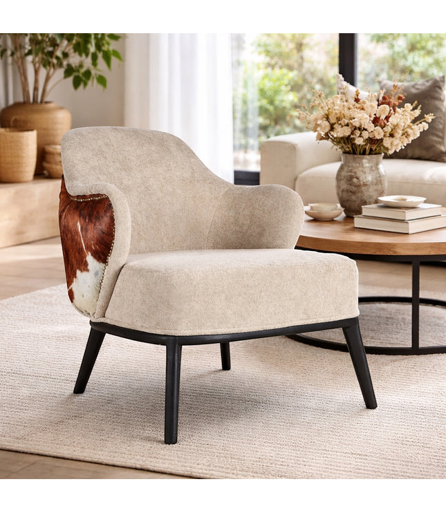 Vaya Home Kalv accent chair with beige upholstery, brown cowhide outer back, and black legs, styled in a bright modern living room.