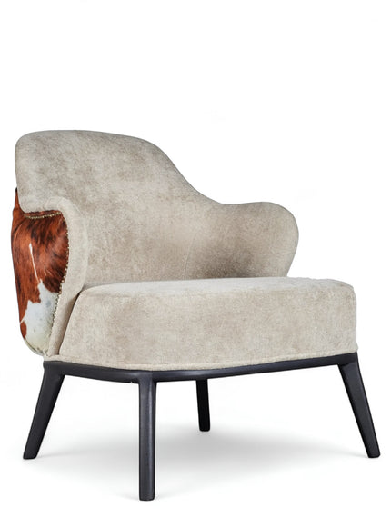 Front angled view of the Vaya Home Kalv accent chair with beige upholstery, curved silhouette, brown cowhide side detail, and black legs.