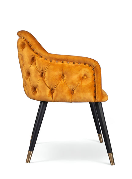 Product view of the Vaya Home Lila accent chair in dark blue velvet upholstery with nailhead trim and black legs with gold caps.