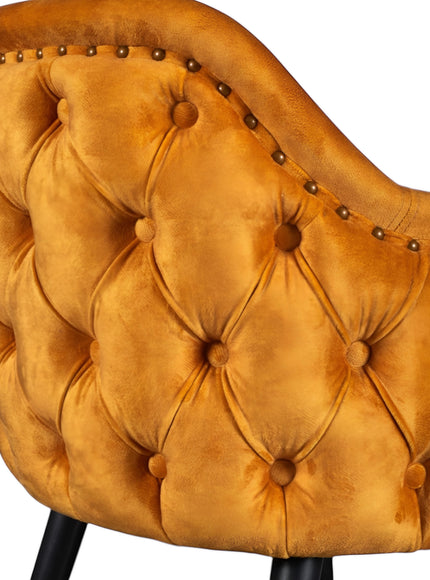 Close-up of the Vaya Home Lila accent chair showing orange velvet upholstery, deep button tufting, and nailhead trim detail.