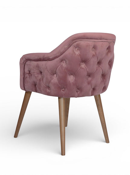 Rear angled view of the Vaya Home Lila accent chair featuring pink velvet upholstery, button-tufted back detail, and tapered wood legs.