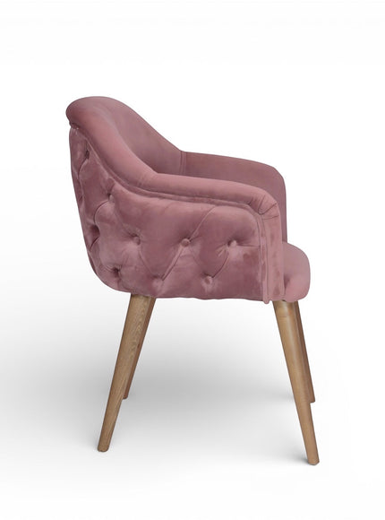 Side view of the Vaya Home Lila accent chair with pink velvet upholstery, button-tufted outer back, and tapered wood legs.