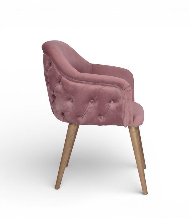 Side view of the Vaya Home Lila accent chair with pink velvet upholstery, button-tufted outer back, and tapered wood legs.