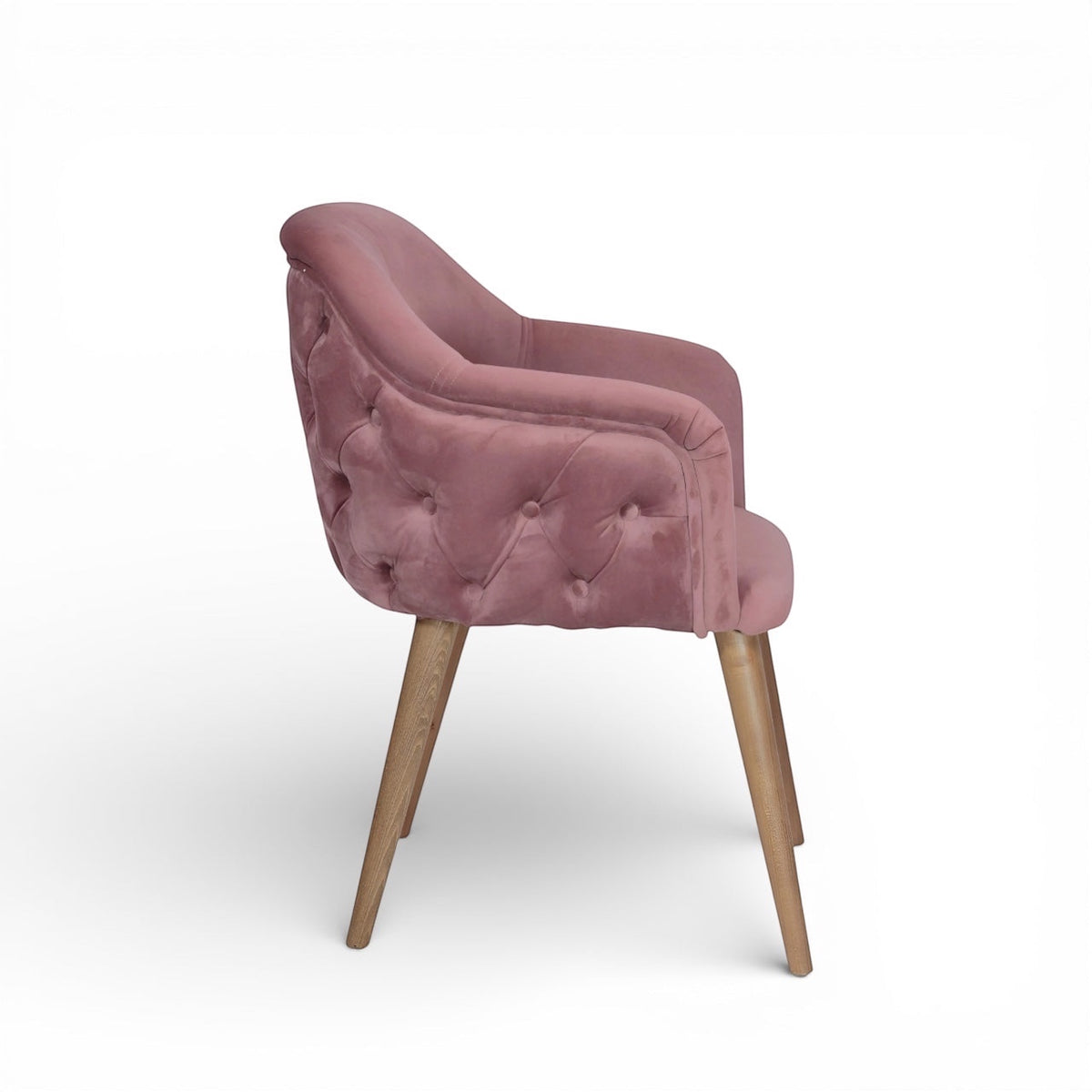 Side view of the Vaya Home Lila accent chair with pink velvet upholstery, button-tufted outer back, and tapered wood legs.