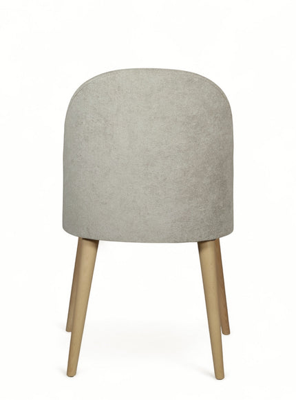 Side view of the Vaya Home Limett dining chair with beige upholstery, rounded backrest, and tapered wood legs.
