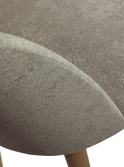 Close-up of the Vaya Home Limett dining chair showing beige upholstery texture and curved backrest detail.