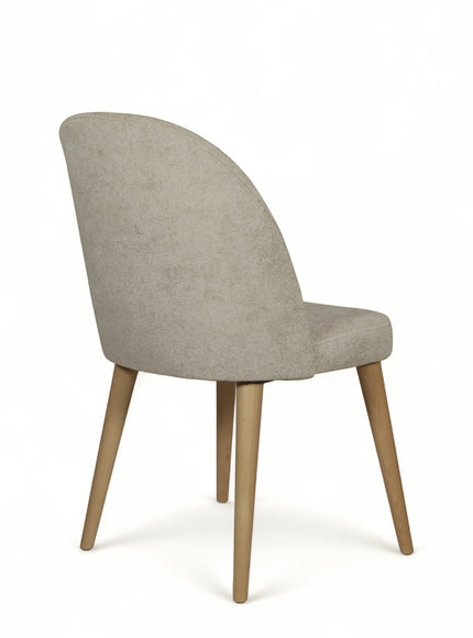 Front angled view of the Vaya Home Limett dining chair with dark blue upholstery, button-back detail, and tapered wood legs.
