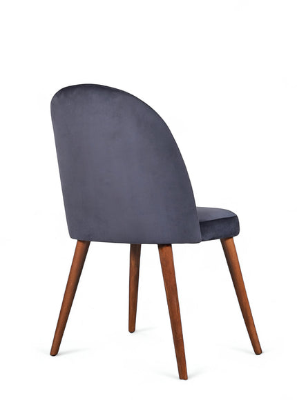 Side view of the Vaya Home Limett dining chair with dark blue upholstery, rounded backrest, and tapered wood legs.