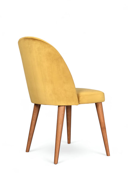 Rear angled view of the Vaya Home Limett dining chair featuring yellow upholstery, a softly curved back, and tapered wood legs.