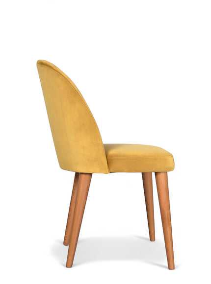 Side view of the Vaya Home Limett dining chair with yellow upholstery, rounded backrest, and tapered wood legs.
