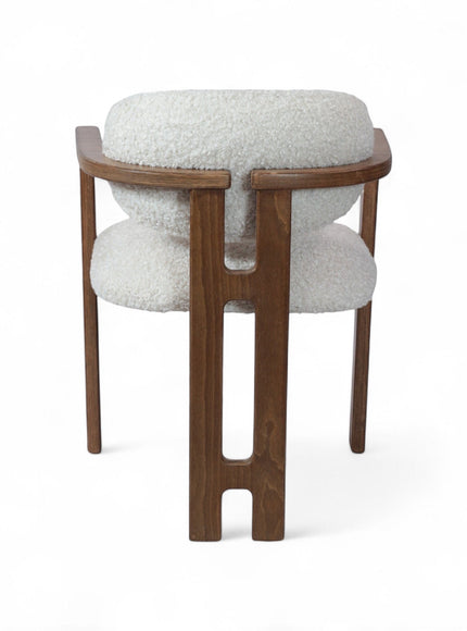 Rear angled view of the Vaya Home Loft dining chair with white boucle upholstery, rounded back cushion, and a warm wood frame.
