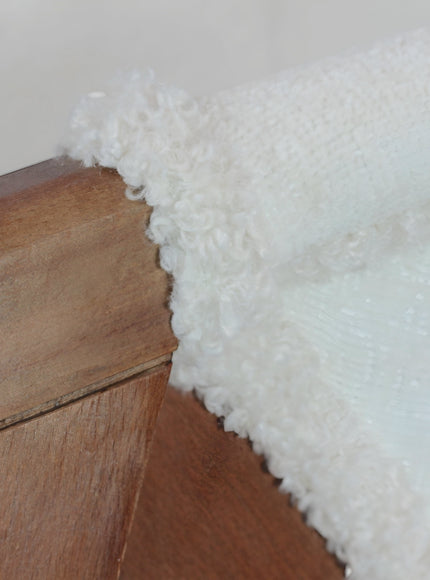 Close-up of the Vaya Home Masiccio dining chair showing white boucle upholstery and wood frame detail.
