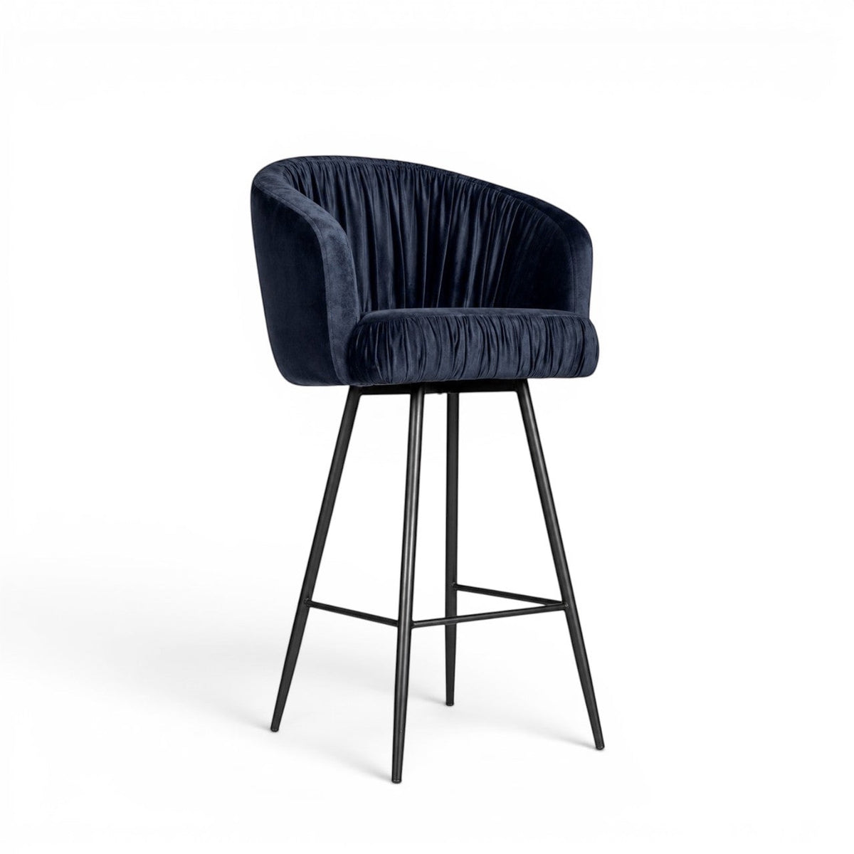 Front angled view of the Vaya Home Midnight bar stool with dark blue velvet upholstery, a channel-tufted curved back, and a black metal base.