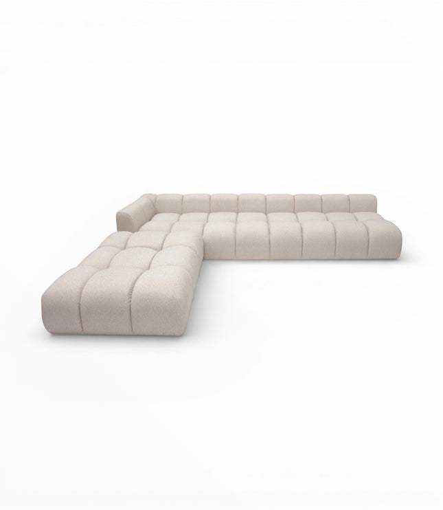 Angled view of the Vaya Home Monolith L-shaped modular sectional sofa with cream upholstery and channel-tufted cushioning.