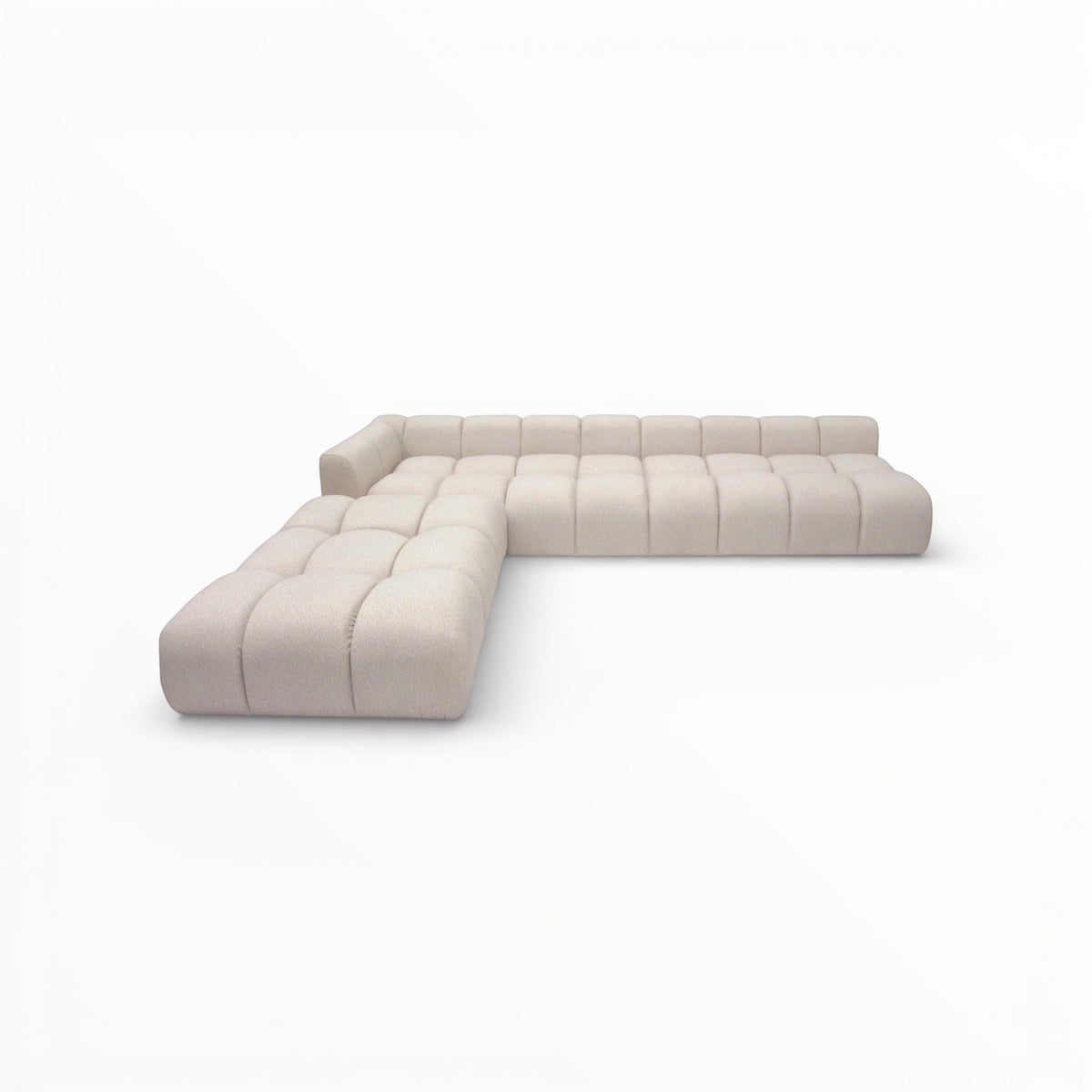 Angled view of the Vaya Home Monolith L-shaped modular sectional sofa with cream upholstery and channel-tufted cushioning.