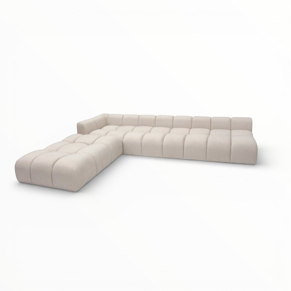 Opposite angled view of the Vaya Home Monolith modular corner sofa featuring cream upholstery and channel-tufted seat and back cushions.