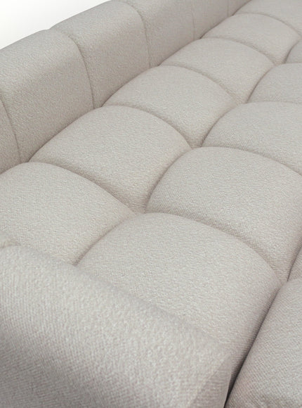 Close-up of the Vaya Home Monolith sofa showing cream textured upholstery and tufted cushion detailing.