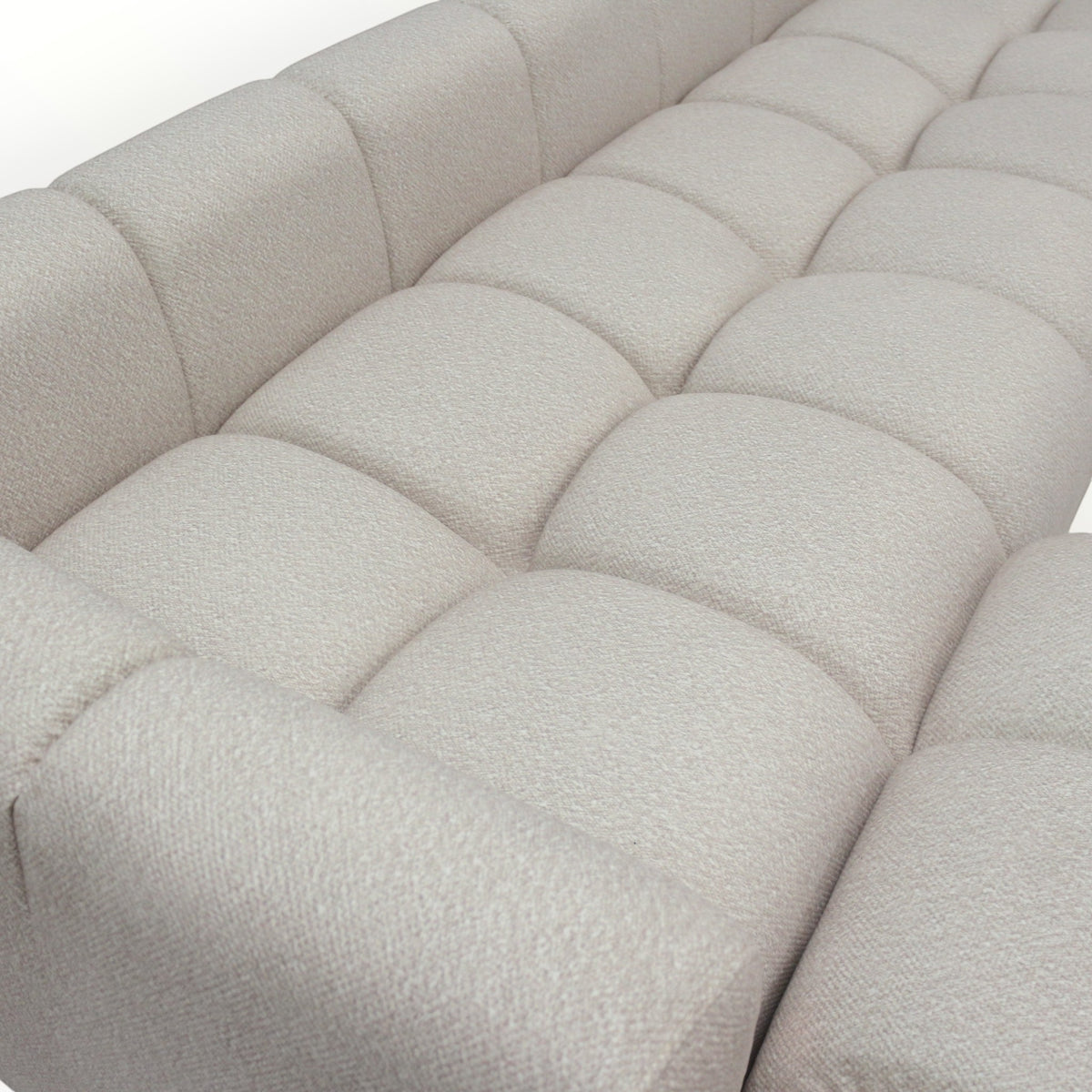 Close-up of the Vaya Home Monolith sofa showing cream textured upholstery and tufted cushion detailing.