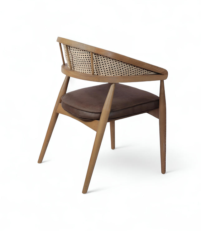Rear angled view of the Vaya Home Morbido dining chair with a woven cane back, dark brown seat cushion, and curved wood frame.