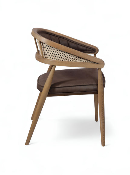 Rear angled view of the Vaya Home Morbido dining chair with a woven cane back, dark brown seat cushion, and curved wood frame.
