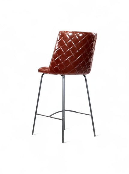 Rear angled view of the Vaya Home Morkrod bar stool with dark brown quilted upholstery and black metal legs.
