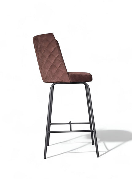 Side view of the Vaya Home Morkrod bar stool featuring rose gold quilted upholstery and black metal legs.
