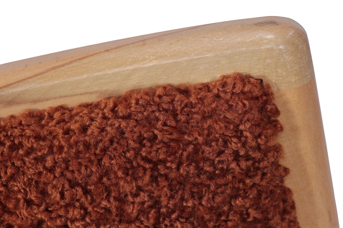 Close-up of the Vaya Home Mouton dining chair showing orange boucle upholstery and wood frame detail.