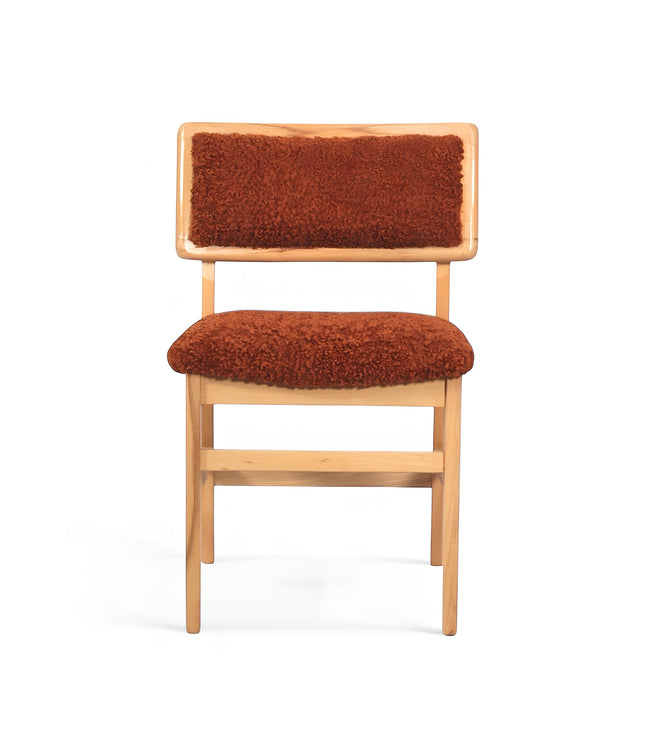 Front view of the Vaya Home Mouton dining chair with orange boucle upholstery and a natural wood frame.