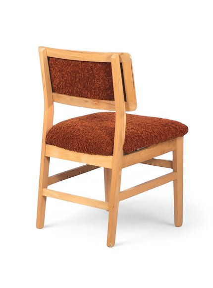 Rear angled view of the Vaya Home Mouton dining chair with orange boucle upholstery and a natural wood frame.