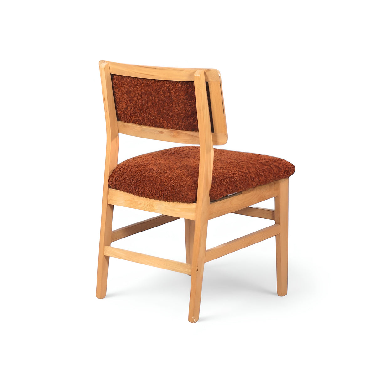 Rear angled view of the Vaya Home Mouton dining chair with orange boucle upholstery and a natural wood frame.