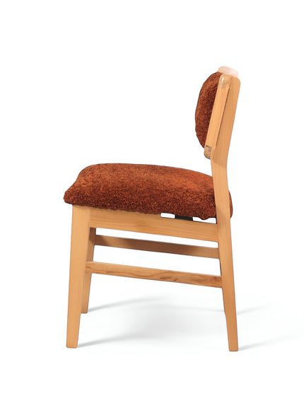 Side view of the Vaya Home Mouton dining chair featuring orange boucle upholstery and a natural wood frame.