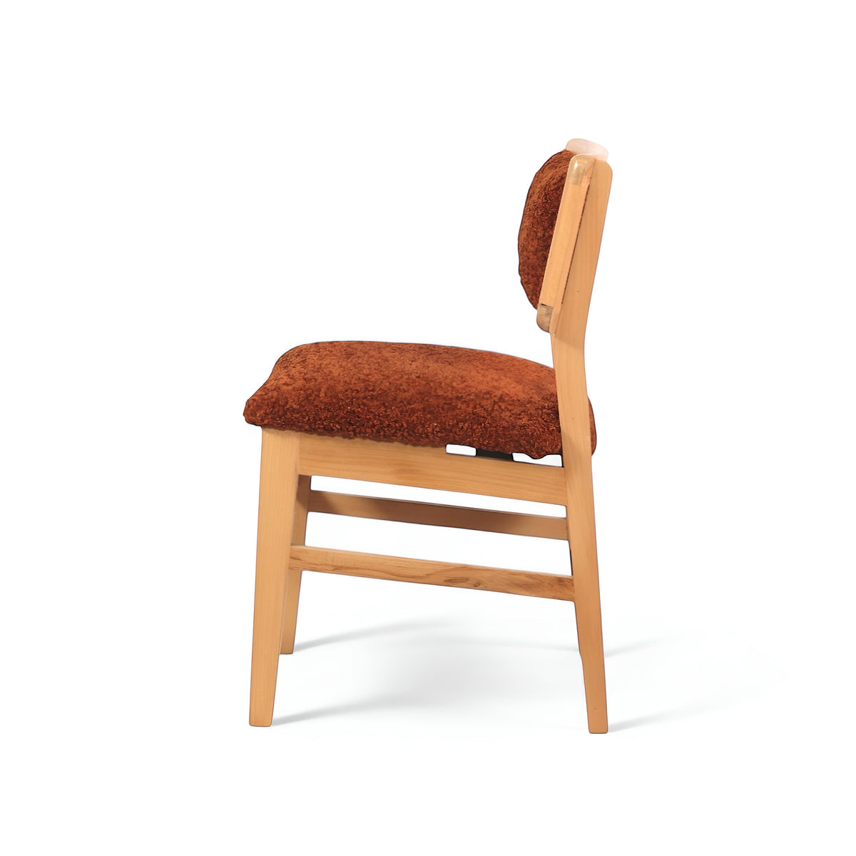 Side view of the Vaya Home Mouton dining chair featuring orange boucle upholstery and a natural wood frame.
